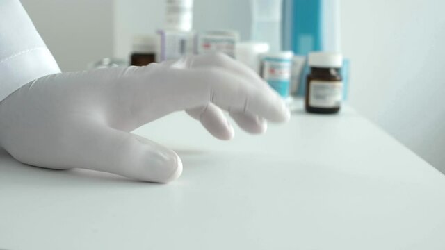 Impatient Doctor Wearing Protective Gloves Makes Nervous Gestures with Fingers on the Desk
