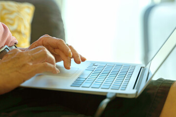 Technology concept, Close-up hands of senior citizen using laptop at home