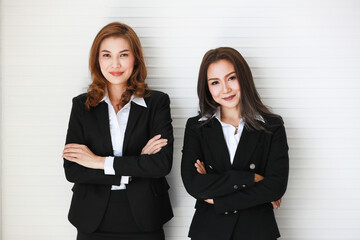 Confident Asian businesswomen against gray wall