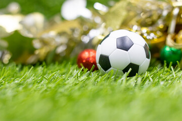 Soccer Christmas Holiday with ball and Christmas decoration on green grass background