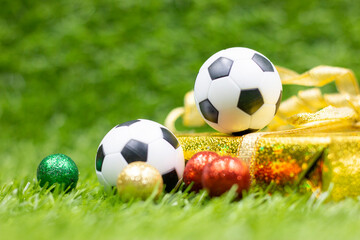 Fototapeta premium Soccer Christmas Holiday with ball and Christmas decoration on green grass background 