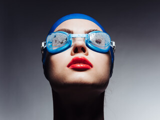 sportswoman with red lips in blue swimming cap and glasses looking up cropped view