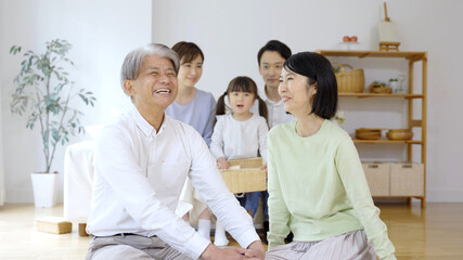 リビングでリラックスする三世代家族