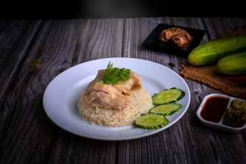 Hainanese chicken rice or Khao Man Gai Asian food in a wood white plate with delicious broth and dipping sauce.
