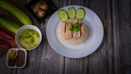 Hainanese chicken rice or Khao Man Gai Asian food in a wood white plate with delicious broth and dipping sauce.