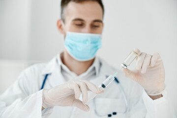 doctor in a medical mask holds a syringe in his hand vaccine chemical liquid covid vaccination