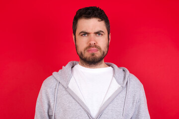 young handsome caucasian man in sports clothes against red background Pointing down with fingers showing advertisement, surprised face and open mouth