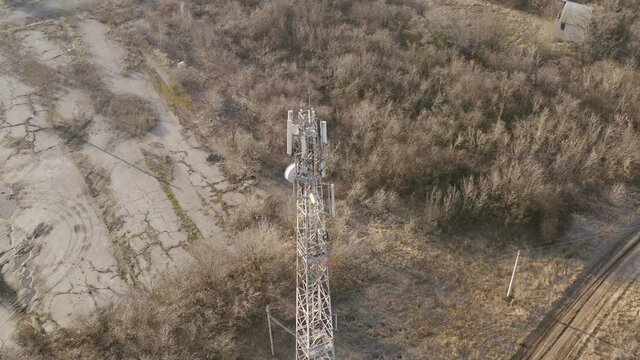 Cellular tower 5G, providing work of mobile operators in rural area - aerial drone orbit shot. Mobile cell tower in the countryside - station of cellular communication.