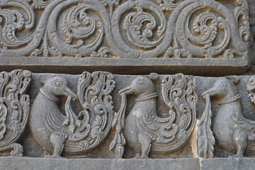 Patterns on the walls of an ancient Indian temple. Stone ornament - Peacocks and flowers.