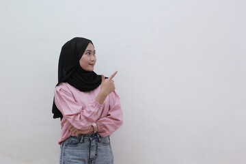 Happy asian muslim woman looking sideways and pointing to copy space. Beautiful asian woman with casual dress. Beautiful muslim women.