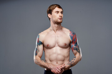 Fototapeta na wymiar sporty man with tattoos on his arms pumped up press macho gray background