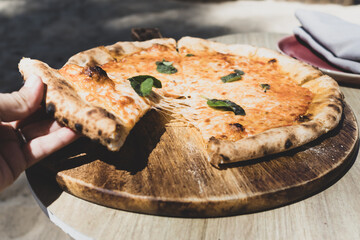 Woman hand taking slice of vegetarian pizza fresh from the pizza oven. Italian cuisine.