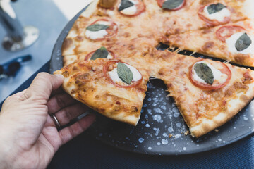 Woman hand taking slice of vegetarian pizza fresh from the pizza oven. Italian cuisine.