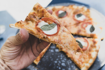 Woman hand taking slice of vegetarian pizza fresh from the pizza oven. Italian cuisine.