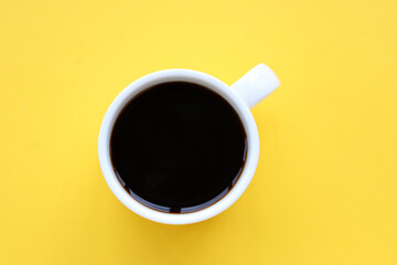Cup of coffee on a yellow background. Top view, copy space