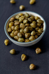 Canned cappers on black stone surface. Gourmet food.