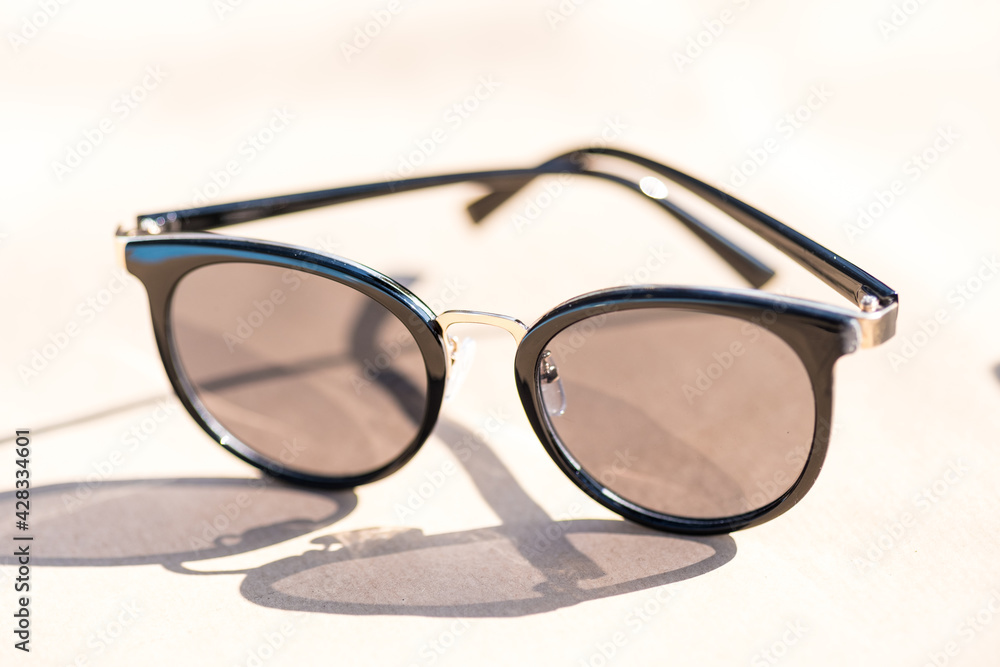 Wall mural Classic sunglasses model for ladies with black round lenses shoot outside in a sunny day closeup . Selective focus. High quality photo