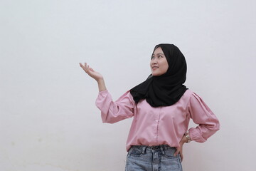 Beautiful asian muslim woman pointing to copy and looking sideways. Beautiful asian woman with casual dress. Beautiful muslim women.