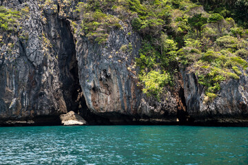 Naklejka na ściany i meble Amazing Large rock cliffs with green tree in the island beach at Thailand. Showing features of sea erosion and cliff recession. Cracks and boulders of rock. Beautiful paradise seascape