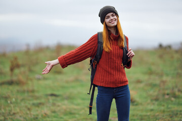 cheerful woman hiker in autumn clothes with a cutter in the mountains landscape on a trip