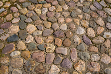 Ancient road paved with natural granite cobblestones. Historic background.