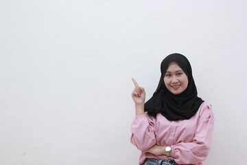 Portrait stylish asian woman smiling on camera and pointing to copy space. Beautiful asian woman with casual dress. Beautiful muslim women.