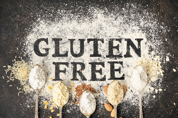 Gluten free written in flour on vintage baking sheet and spoons of various gluten free flour almond...