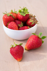 Red juicy strawberries. seasonal berries in white bowl on wooden background.Vertical format