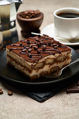 Portion of Traditional Italian Tiramisu dessert and mocha coffee maker on grey concrete background