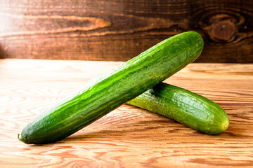 two green cucumbers on the wooden surface of the table