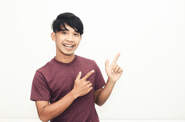 Asian man smiling in casual t-shirt while pointing at empty space