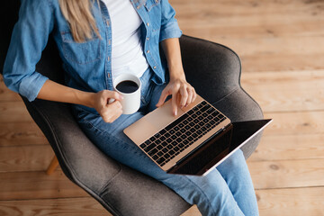 Slim young woman working on laptop and having coffee