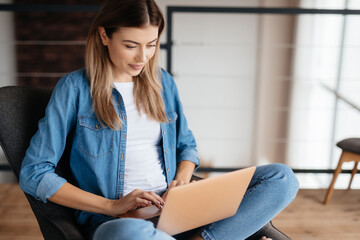Pretty fair-haired lady working on her laptop at home