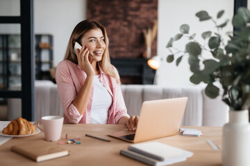 Contented lady having phonecall while working from home