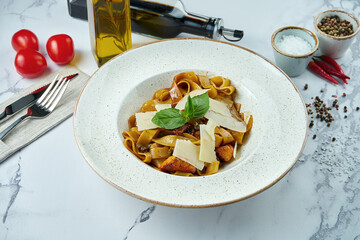 Appetizing Italian pasta with salmon, sun-dried tomatoes and parmesan in a white plate on a marble background. Fettuccine with seafood