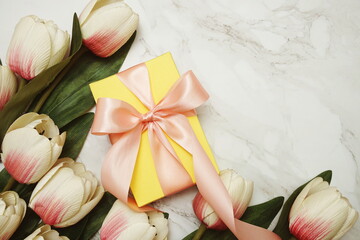 Gift boxes with pink ribbon and tulip flower bouquet on marble background