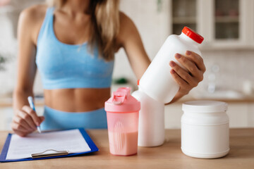 Slender young lady taking notes about food supplements