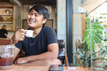 Portrait of asian man sitting in the coffee cafe with using the smartphone. The man smiling in the coffee shop.