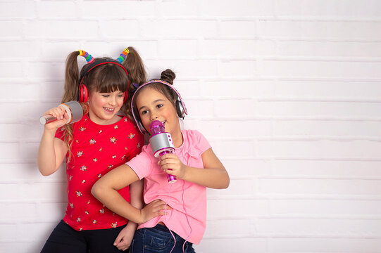 Two little girl with a microphone  singing together and playing