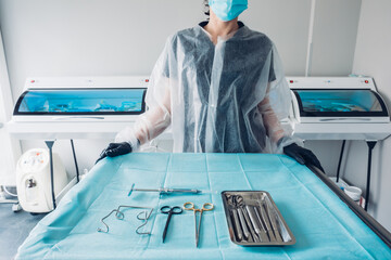 Nurse preparing table with set of sterile surgical instruments for a dental surgery