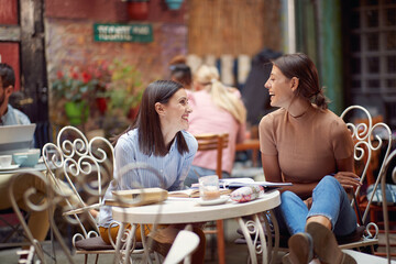 Two female students having a good time while have a drink in bar's garden. Leisure, bar, friendship, outdoor