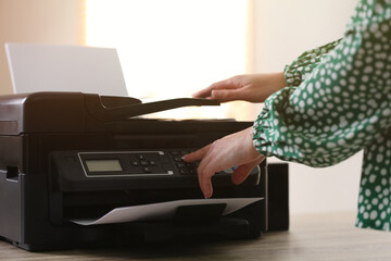 Woman using modern printer in office, closeup