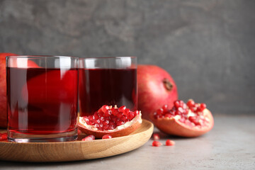 Pomegranate juice and fresh fruits on grey table, space for text
