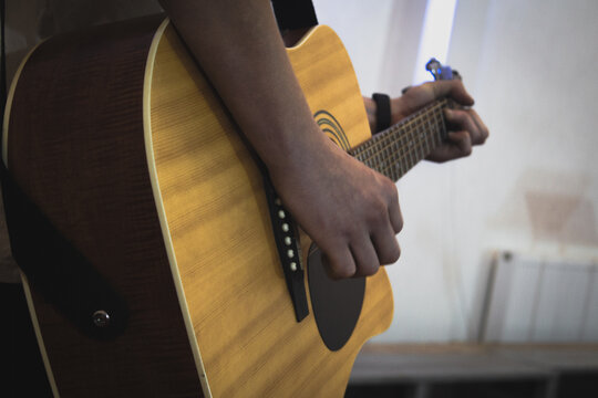 Yellow acoustic guitar close up playing music on musical instruments background. Fretboard with strings