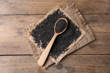 Fototapeta premium Black sesame seeds and spoon on wooden table, flat lay