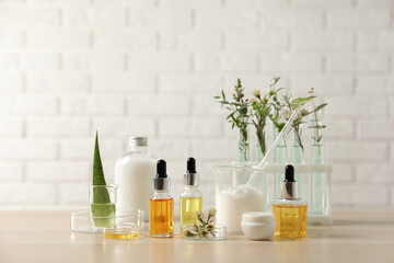 Organic cosmetic products, natural ingredients and laboratory glassware on wooden table