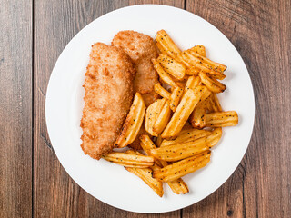 Classic fish and chips dish on a wooden table. Top down view.