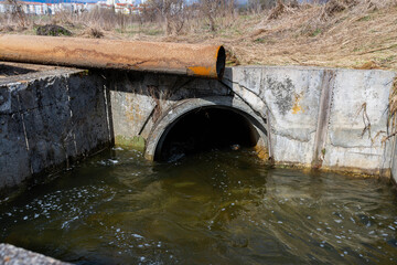 Fast flowing sewage water in a concrete pit near a small town .