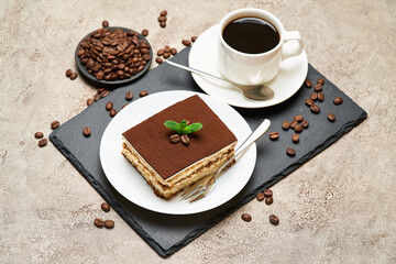 Portion of Traditional Italian Tiramisu dessert and cup of coffee on grey concrete background