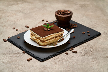 Portion of Traditional Italian Tiramisu dessert on grey concrete background